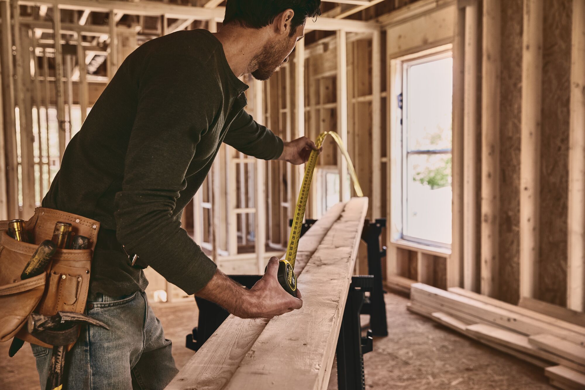 25 foot FATMAX classic tape measure being used by a person to measure length of a wooden plank.