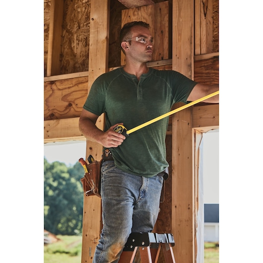 25 foot FATMAX classic tape measure being used by a person at a work station.