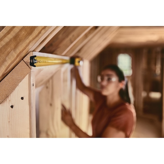 25 foot FATMAX classic tape measure being used by a person to measure wood length.