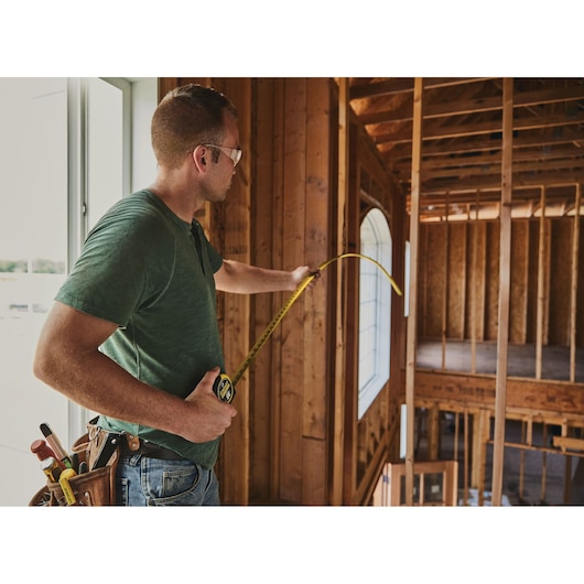 25 foot FATMAX classic tape measure being used by a person in a construction site.