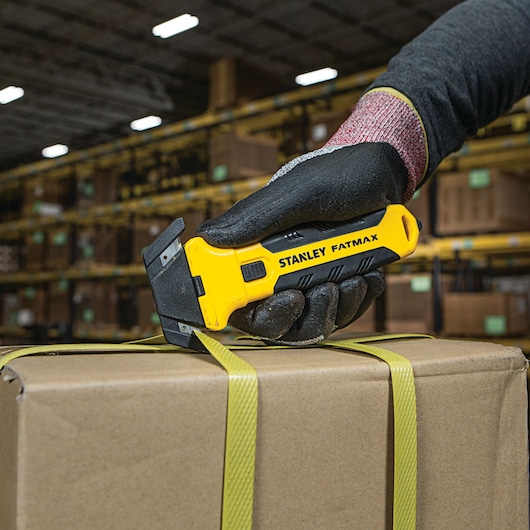 Fatmax double sided replaceable head pull cutter being used to cut straps on a box.