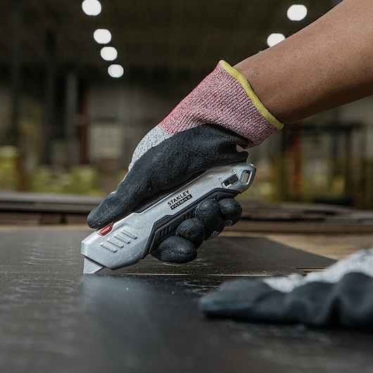 Fatmax premium auto retract squeeze safety knife being used to cut a sheet.
