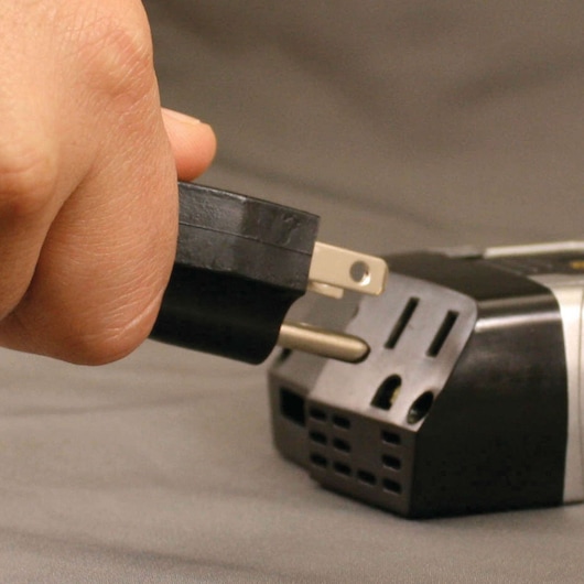 120 watt power inverter with AC and USB chargers being plugged in by a person.