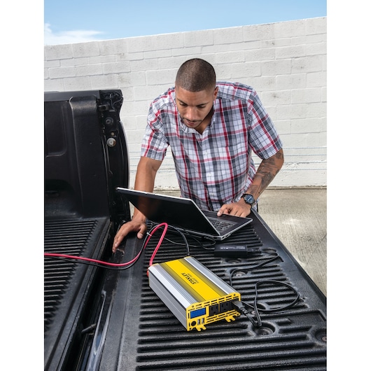 1000 watt power inverter with USB being used by a person to charge a laptop.