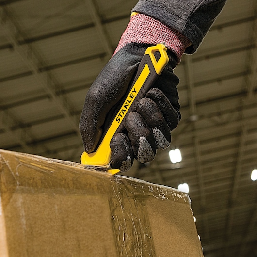 SINGLE SIDED BI MATERIAL PULL CUTTER being used for cutting cello tape on box.