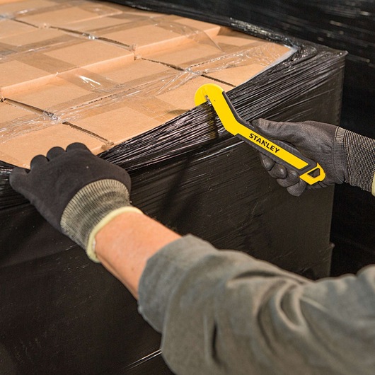 SINGLE SIDED ROUND TIP BI MATERIAL PULL CUTTER being used for cutting plastic packing on cardboard boxes.