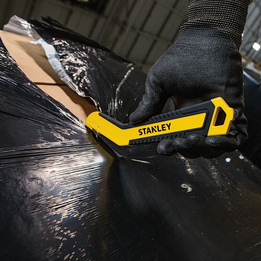 SINGLE SIDED ROUND TIP BI MATERIAL PULL CUTTER being used for cutting plastic packing on cardboard box.