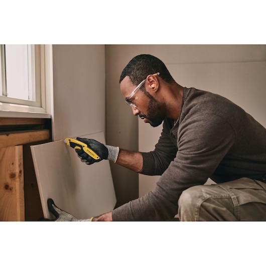Retractable Utility Knife being used for cutting plywood.