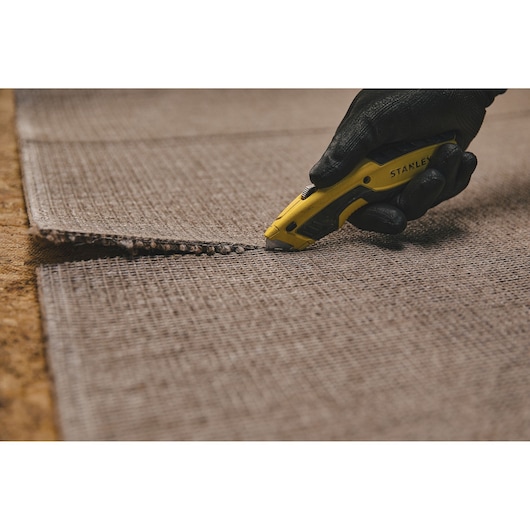Retractable Utility Knife being used for cutting carpet.