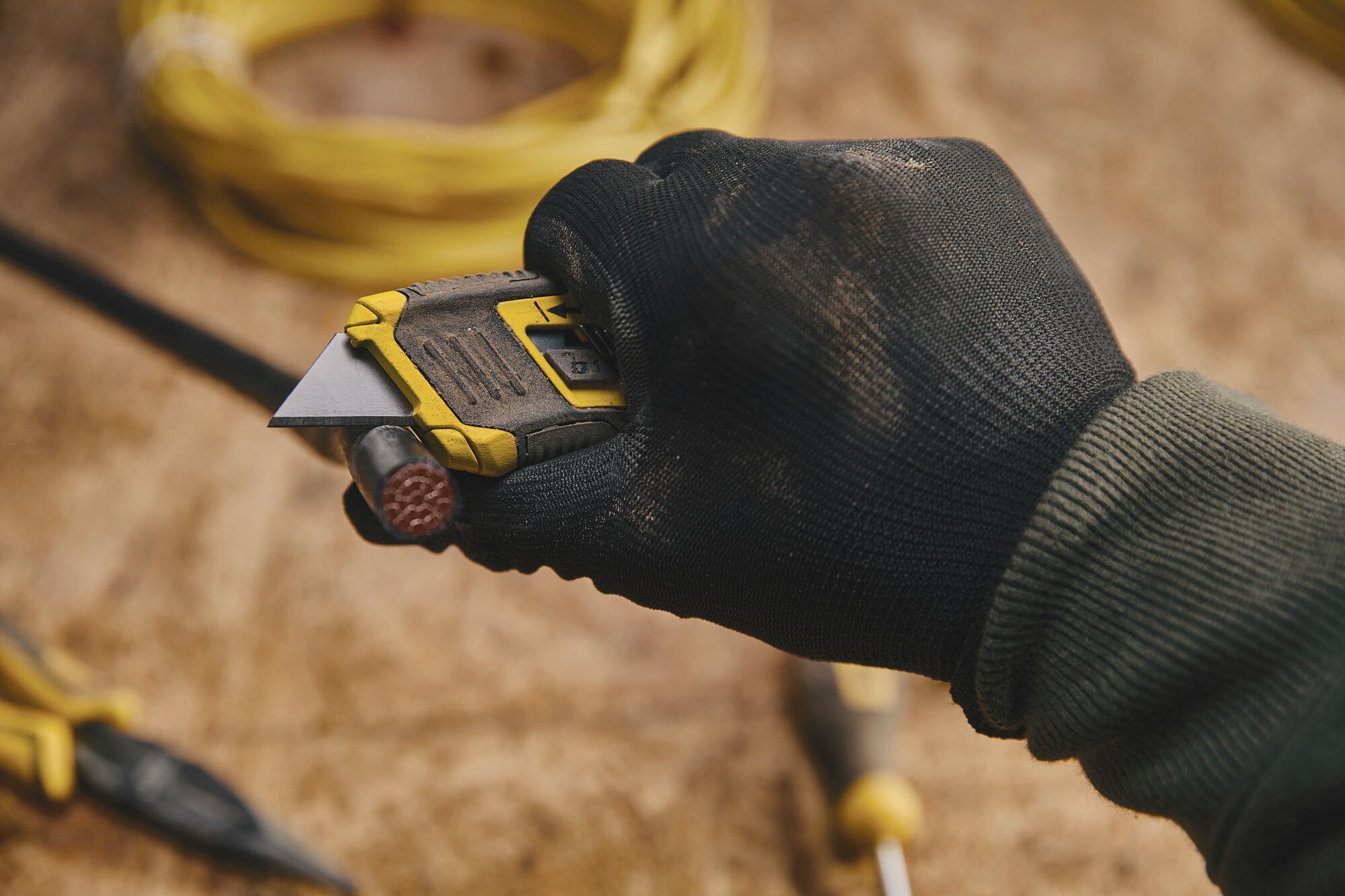 CONTROL GRIP RETRACTABLE UTILITY KNIFE being used for cutting wire.
